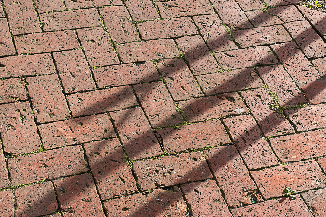 Post shadows on brick sidewalk